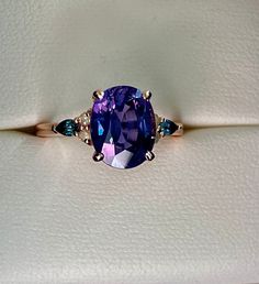 "Purple blue color change sapphire ring by Eidelprecious. This ring features a 4 oval sapphire, amazing deep indigo blue purple color. Displays color change. Very unique and rare one of a kind sapphire. This beauty is set in our newest 2022 Campari setting. 4 round yellow diamonds And 2 pear teal sapphires. Size 6, can be resized If you like this ring, please press \"Pin it\" button on the right of your screen. Thanks!" Color Change Sapphire Engagement Ring, Tanzenite Engagement Ring, Tanzanite And Sapphire Ring, Sapphire Amethyst Ring, Tanzanite Ring Unique, Amethyst And Sapphire Ring, Tanzanite Engagement Rings, Wedding Rings With Colored Stones