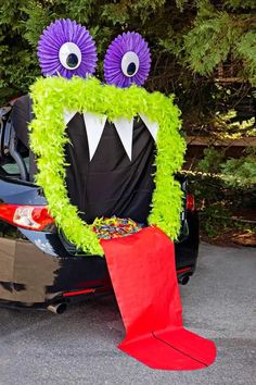 a car decorated to look like a monster with large eyes and green grass on the trunk