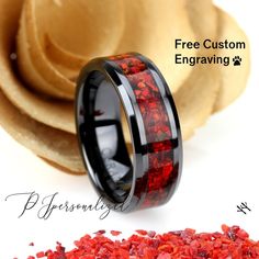 the black ceramic ring with red flowers inlays is next to a pile of wood chips