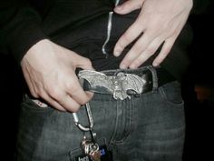 a man is holding onto his belt with a metal bird keychain on it