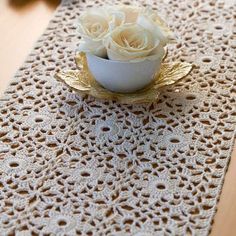 white roses in a small bowl on a doily table runner with crochet