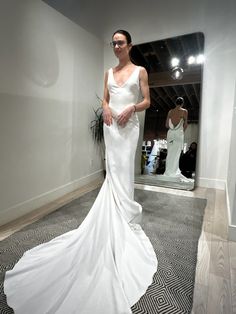 a woman standing in front of a mirror wearing a white dress