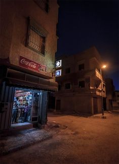 an empty street at night in front of a building with a coca cola sign on it