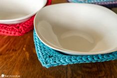 two white bowls sitting on top of a wooden table next to blue and pink placemats