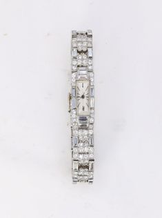 11-carat platinum & diamond Art Deco watch Art-Deco watch in platinum and diamonds. The articulated bracelet entirely set with diamonds creates a geometric pattern. This is composed of alternating links featuring four-leaf clovers on the one hand and two openwork baguette-cut diamonds on the other. The case is also entirely set with brilliant-cut and baguette-cut diamonds. The long dial and the typography of the numbers are typical of the period. The manual winding mechanical movement is not signed but is noted "Swiss Made, 15 jewels". French work from the Art-Deco period made between 1932 and 1936. Presence of the dog's head hallmark for a French platinum jewel and manufacturer's hallmark P K two clovers for Pavel Koiran.  The clover patterns are represented by 12 good quality round diamo Watch Art, Art Deco Watch, Baguette Cut Diamond, Art Deco Period, Mechanical Movement, Baguette Cut, Women Wrist Watch, Diamond Watch, Baguette Diamond