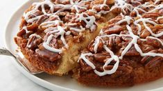 a cake with white frosting and pecans on top is sitting on a plate