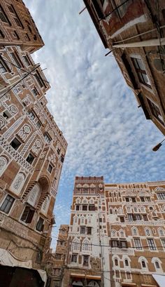 some very tall buildings with windows and balconies on the sides under a cloudy blue sky