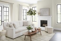 a living room filled with furniture and a fire place in front of a window covered in white curtains