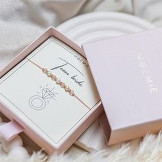 a pink box with a bracelet in it sitting on top of a white furnish