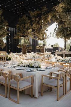 the tables are set with white flowers and place settings for an outdoor dinner party or reception