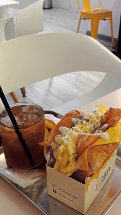 a tray with a sandwich and drink on it sitting on a table next to a chair