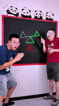 two young men standing in front of a blackboard with pandas drawn on it