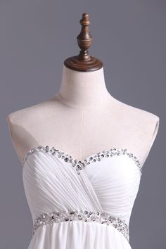 a strapless white dress on a mannequin with beading and pleating