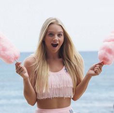 a woman holding two pink cotton candy lollipops