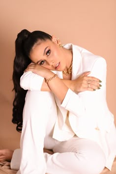 a woman in white is posing for the camera with her hands on her knees and arms crossed