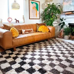 a living room with a couch, rug and potted plants on the side wall