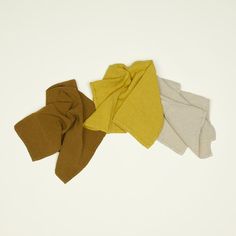 four different colors of scarves on a white surface with one folded over the other