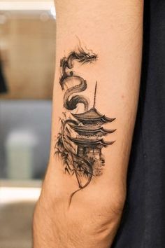 a tattoo on the arm of a man with a dragon and pagoda in the background