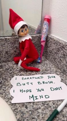 an elf with a toothbrush sitting on a counter next to a sign that says i bought your mouth brush, hope you don't mind