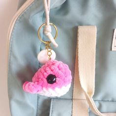 a pink and white crocheted keychain hanging from a blue bag