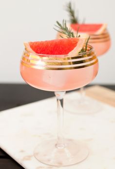 two glasses filled with watermelon and garnish on top of a table