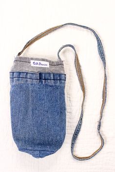 a blue jean purse with a white label on the front pocket and a brown cord attached to it