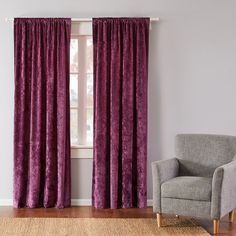 a chair sitting in front of a window with purple curtains