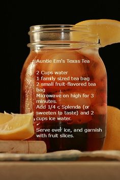 a mason jar filled with tea sits next to sliced lemons