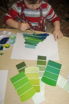 a little boy that is sitting at a table with some paint swatches on it