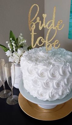 a cake with white frosting and gold lettering on top, sitting on a table