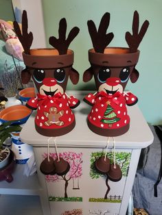 two reindeer planters sitting on top of a white cabinet next to each other,