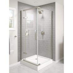 a bathroom with a walk in shower next to a white tiled wall and flooring