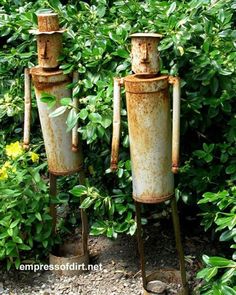 two rusty metal art sculptures sitting in front of green plants and bushes with the words metal yard art gallery written below them