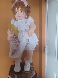 a doll sitting on top of a wooden table next to a wall with an open door