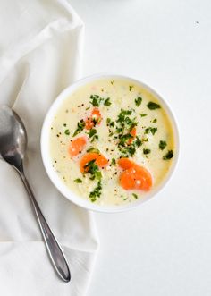 a bowl of soup with carrots and parsley in it on a white cloth