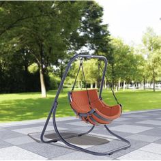 an orange swing chair in the middle of a park