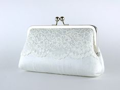 a white clutch bag with lace on the front and back side, sitting on a table