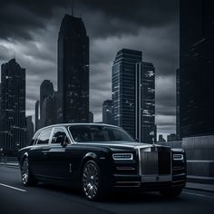 a black and white photo of a rolls royce parked in front of a cityscape