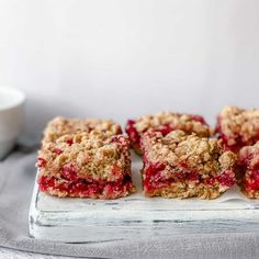 four pieces of strawberry crumbler bars on a tray next to a cup of milk