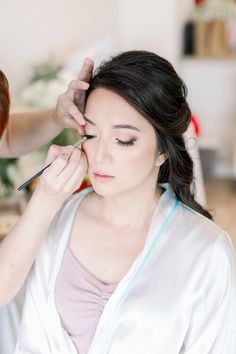 a woman getting her makeup done by another woman