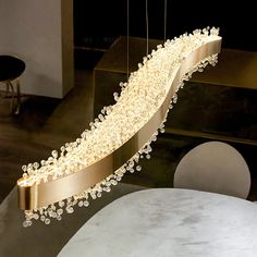 a chandelier hanging from the ceiling in a room with marble tables and chairs