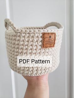 a hand holding a crocheted basket with a wooden button on the front and bottom