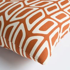 an orange and white pillow on a white surface