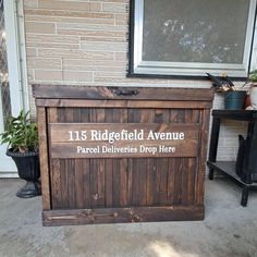 a large wooden box sitting on the side of a building next to a potted plant