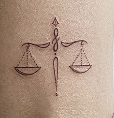 a tattoo on the back of a woman's leg with scales and an arrow