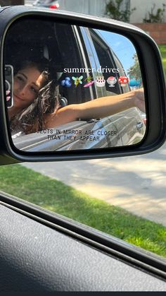 a rear view mirror on the side of a car showing a woman's reflection