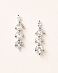 two pairs of earrings with white pearls and crystal stones on top of each earring