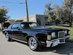 an old black car is parked on the street