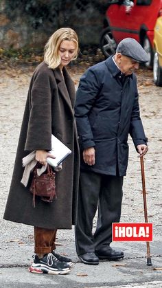 an older man and woman standing next to each other with a sign that says hola