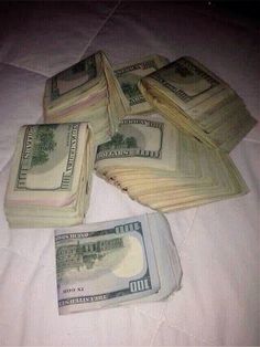 five stacks of one hundred dollar bills laid out on top of each other in the middle of a bed